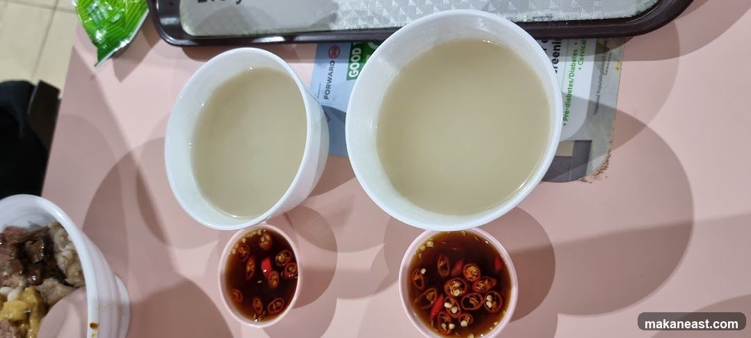Two bowls of soup with chili dipping sauce