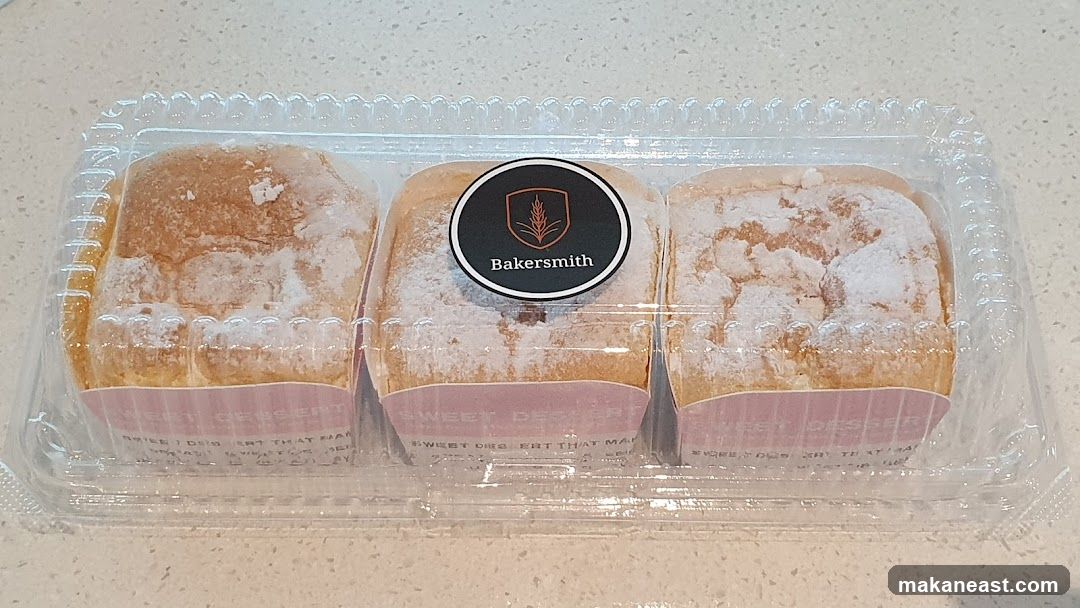 Three powdered pastries in a plastic container