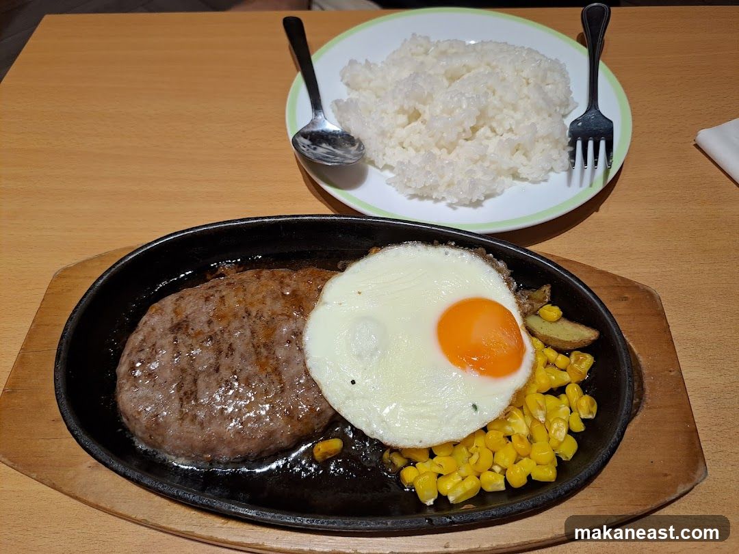 Hamburger steak with fried egg, rice, corn, and potatoes