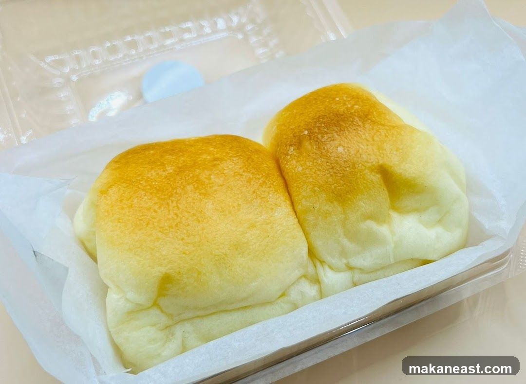 Two golden-brown buns in a clear plastic container lined with white paper.