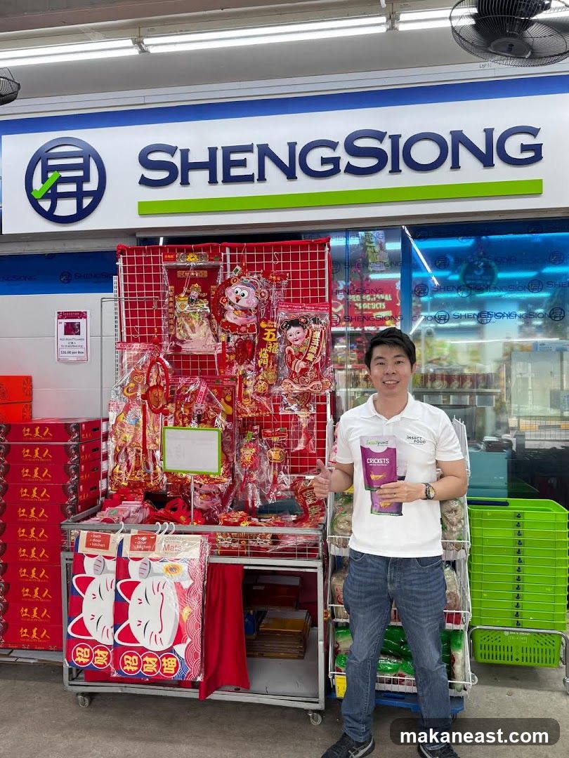 Man holding cricket snacks in front of Sheng Siong supermarket display