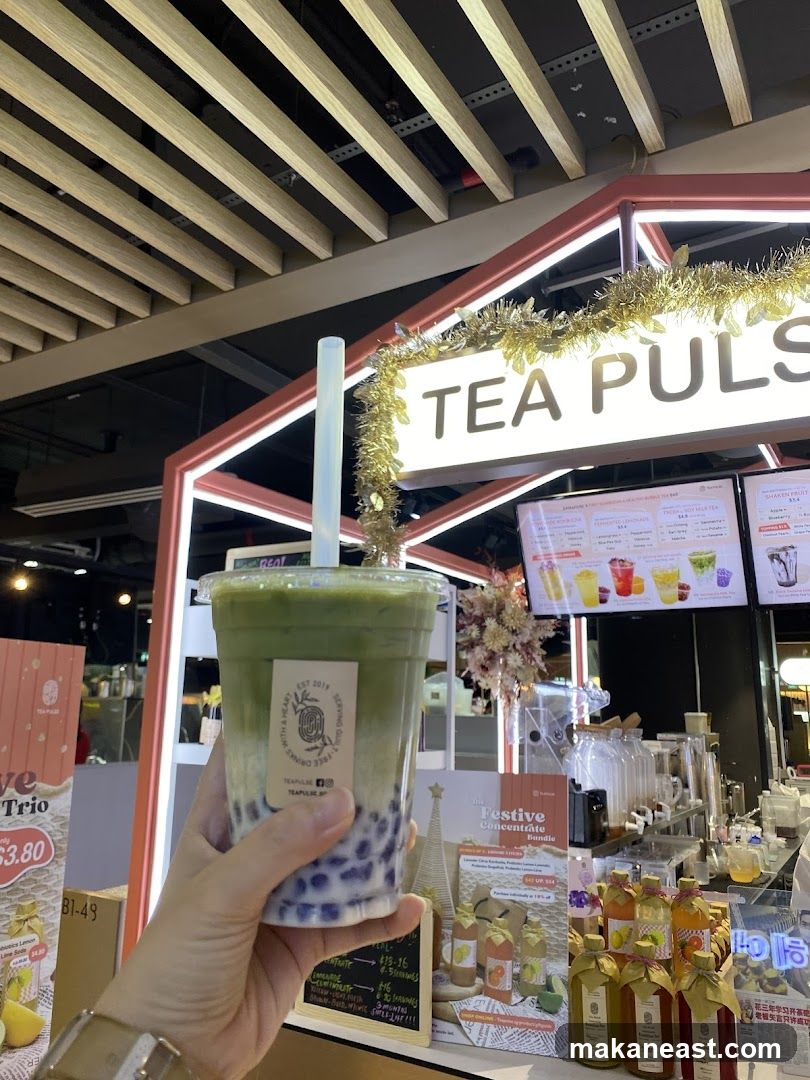 Person holding a bubble tea in front of a Tea Pulse store