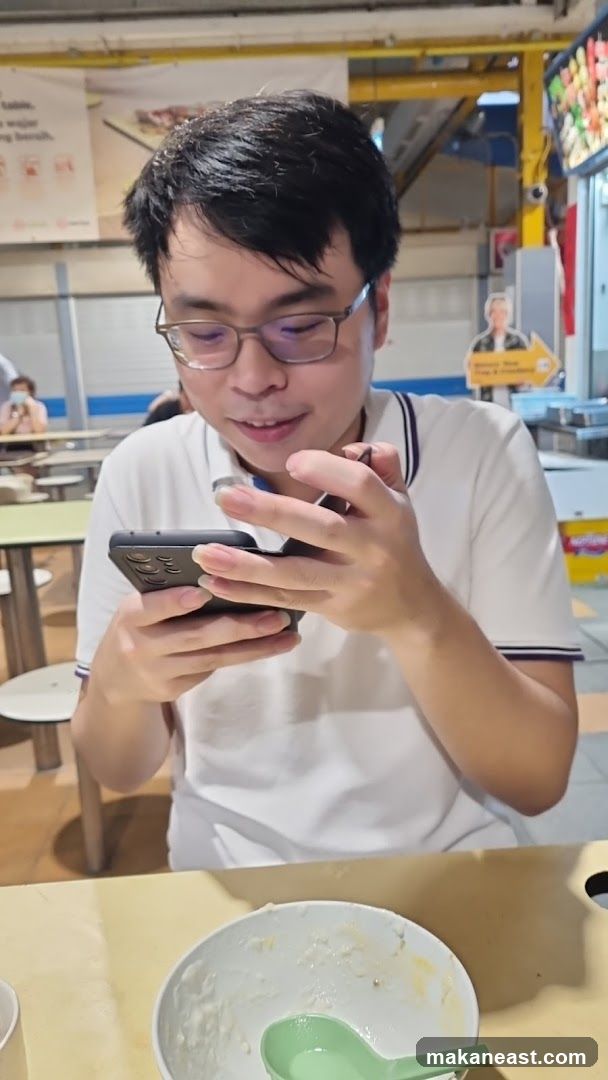 Man looking at phone at food stall