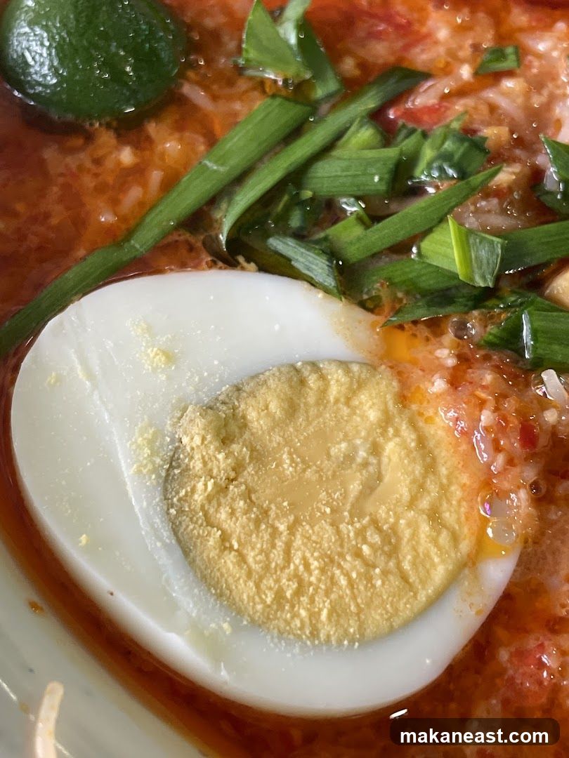 Close-up of a bowl of noodles with a hard-boiled egg and lime