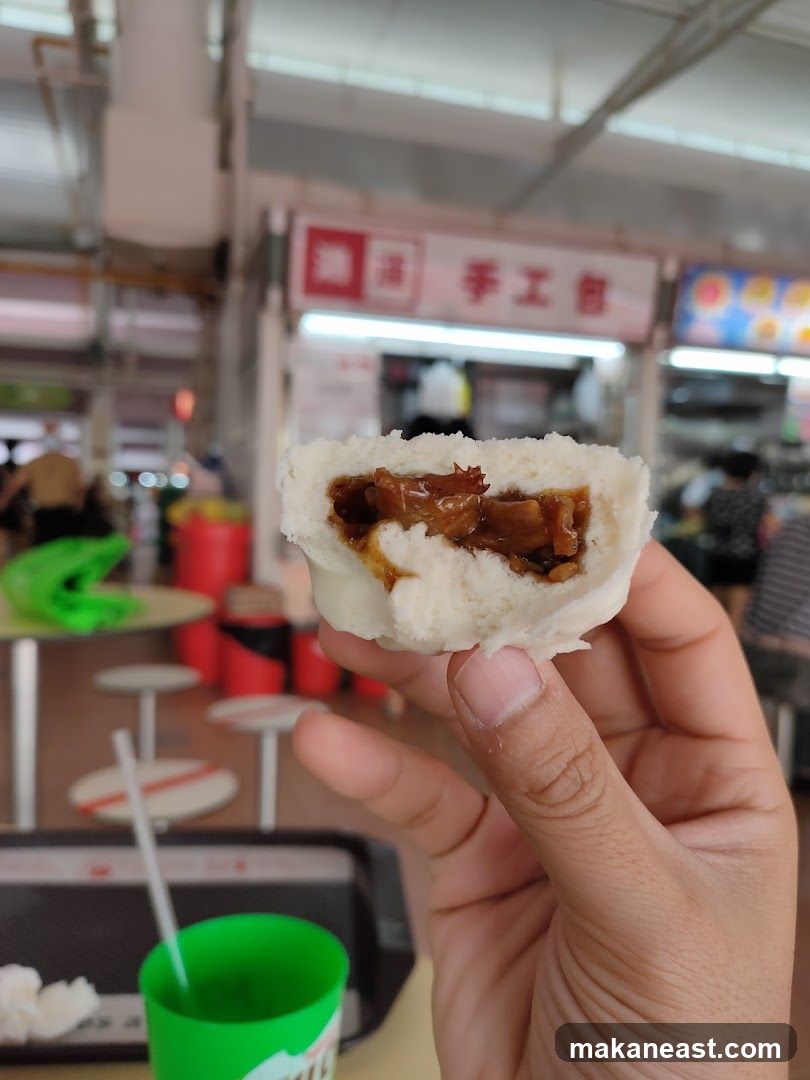 Hand holding a steamed bun with filling
