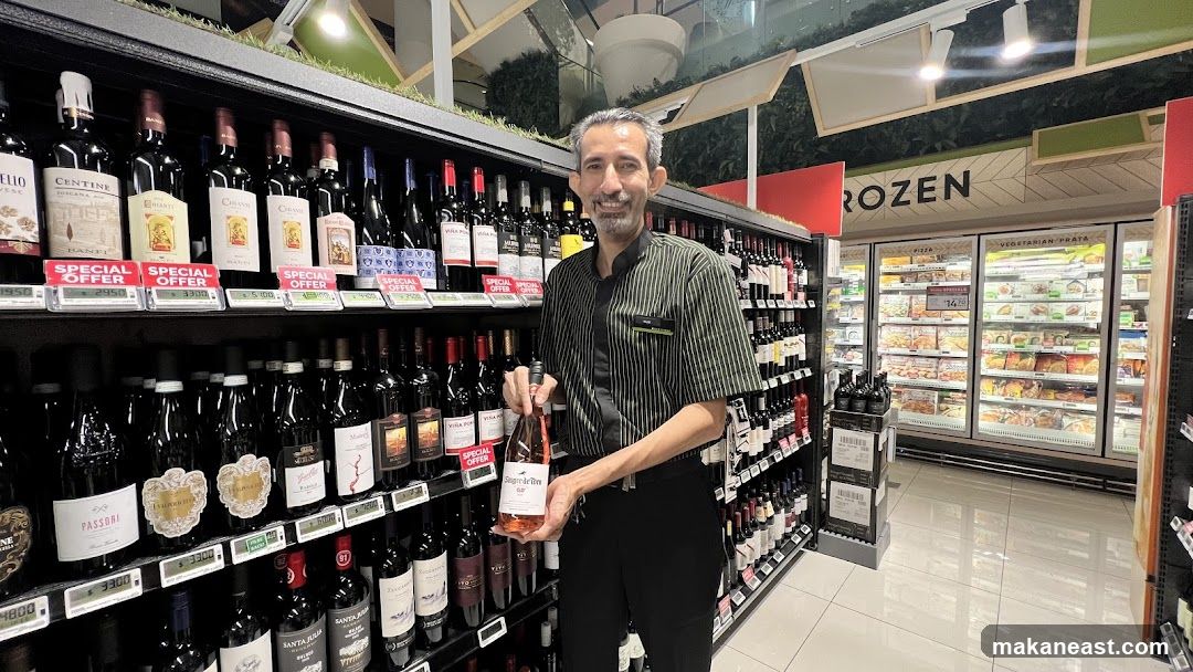 Man holding a bottle of rose wine in a supermarket aisle