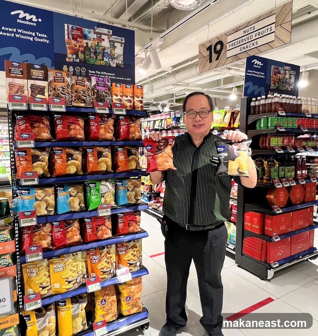 Man holding snacks in a supermarket aisle