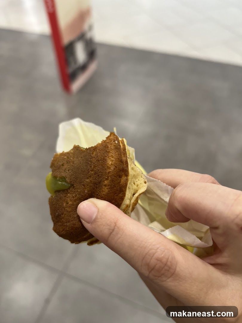 Hand holding a bite-sized pancake with green filling
