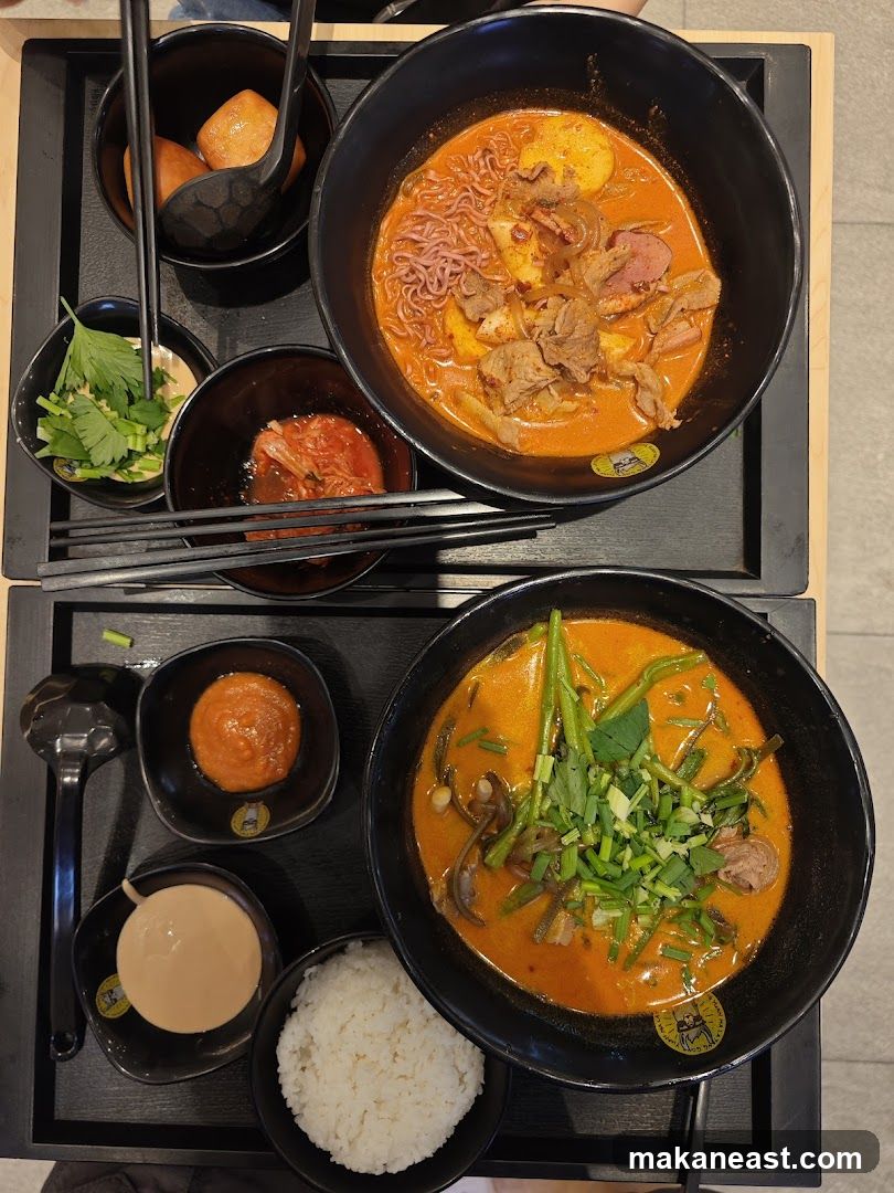 Two bowls of spicy noodle soup with side dishes