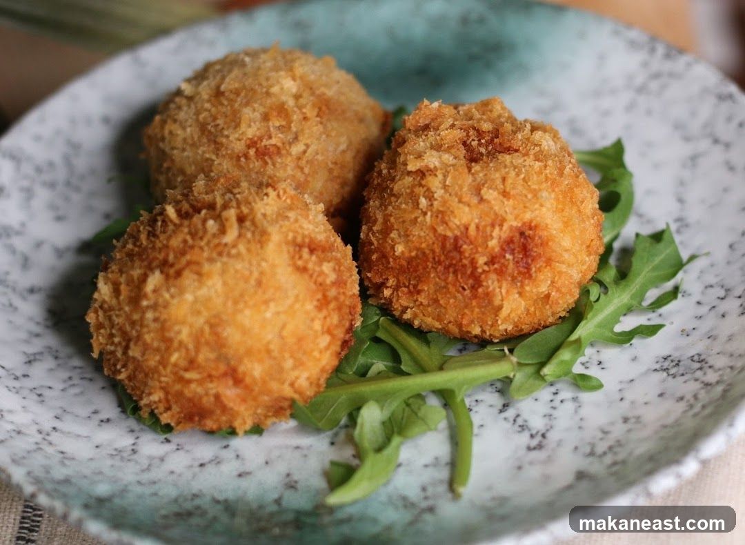 Three fried croquettes on a bed of arugula