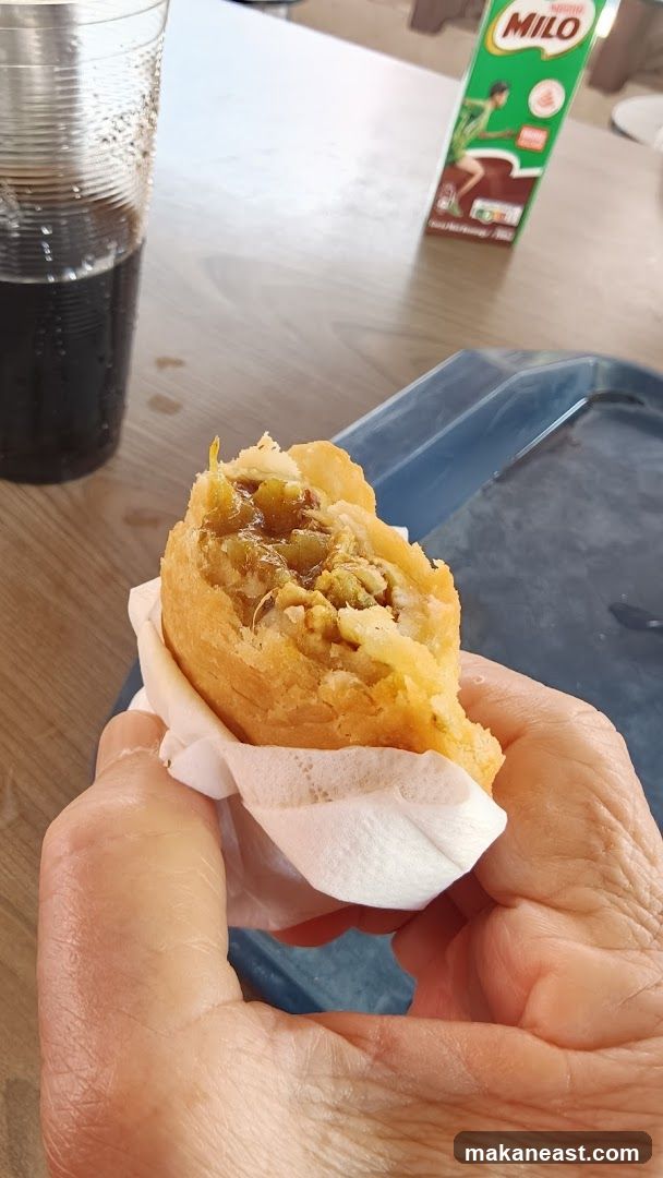 Hand holding a pastry with a drink and Milo carton
