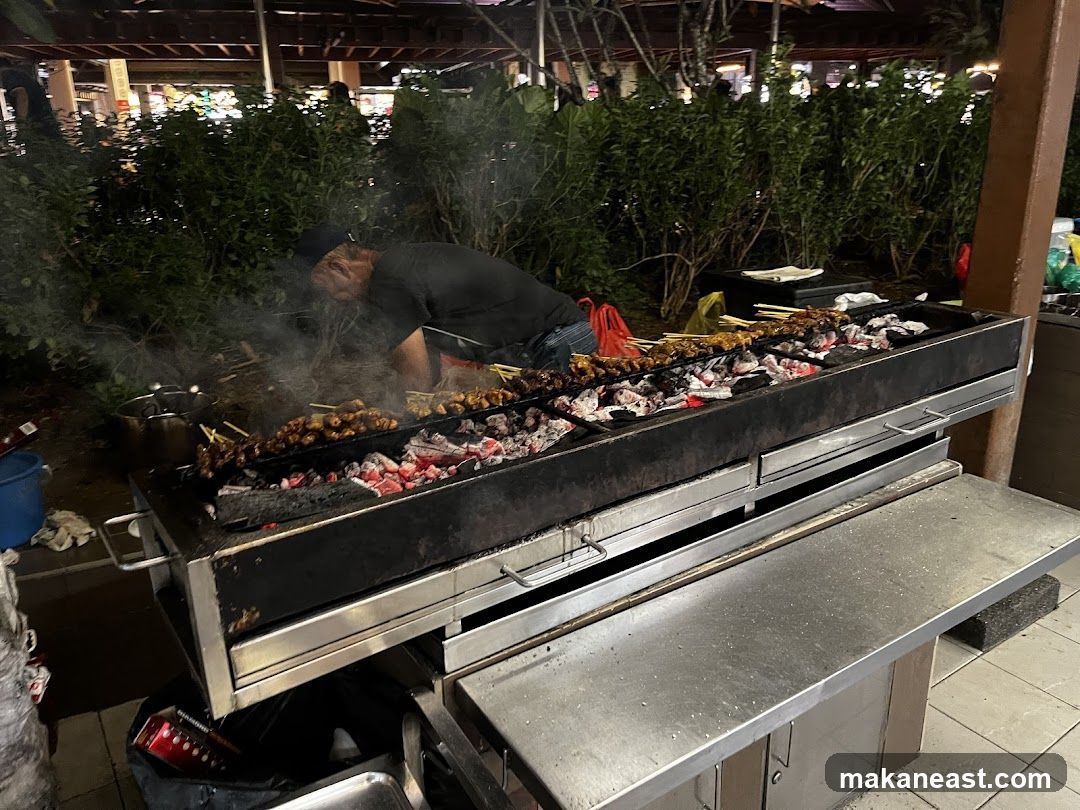 Man grilling skewers over coals