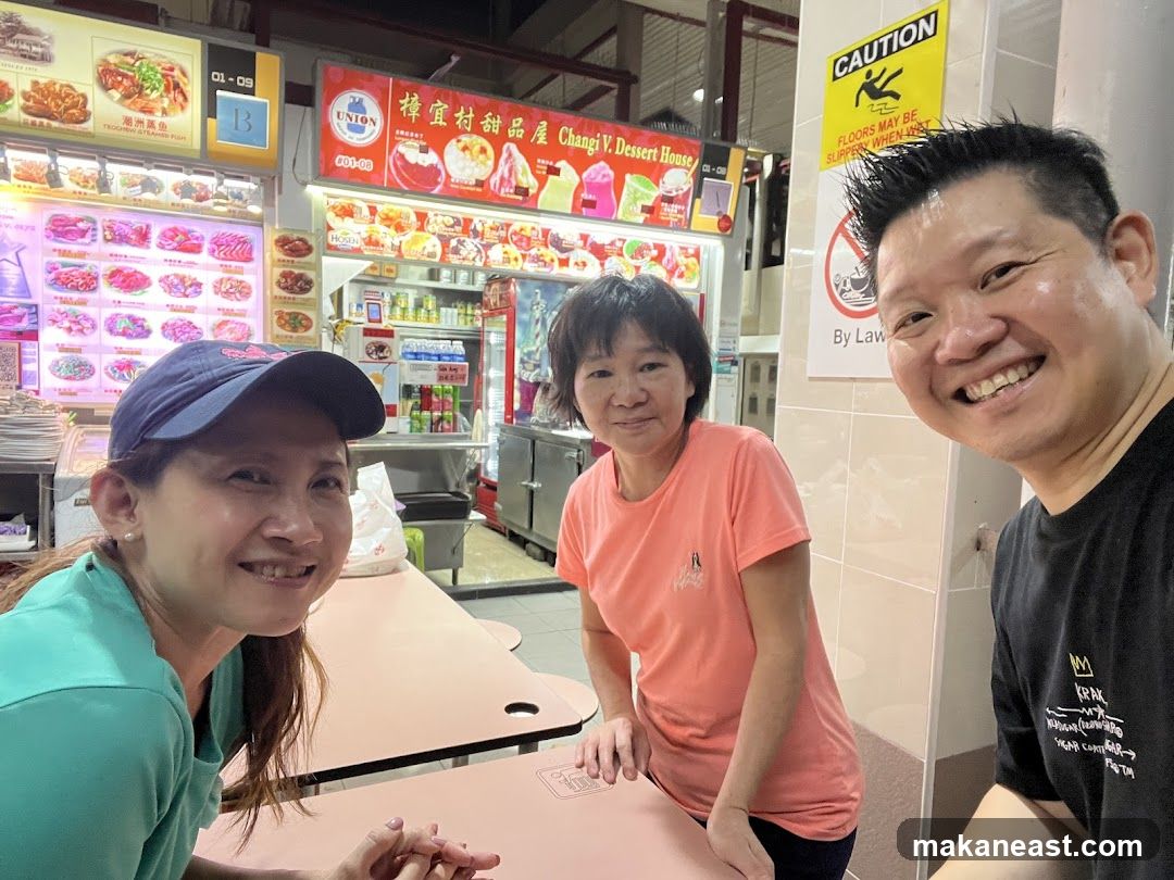 Three people smiling at a food stall