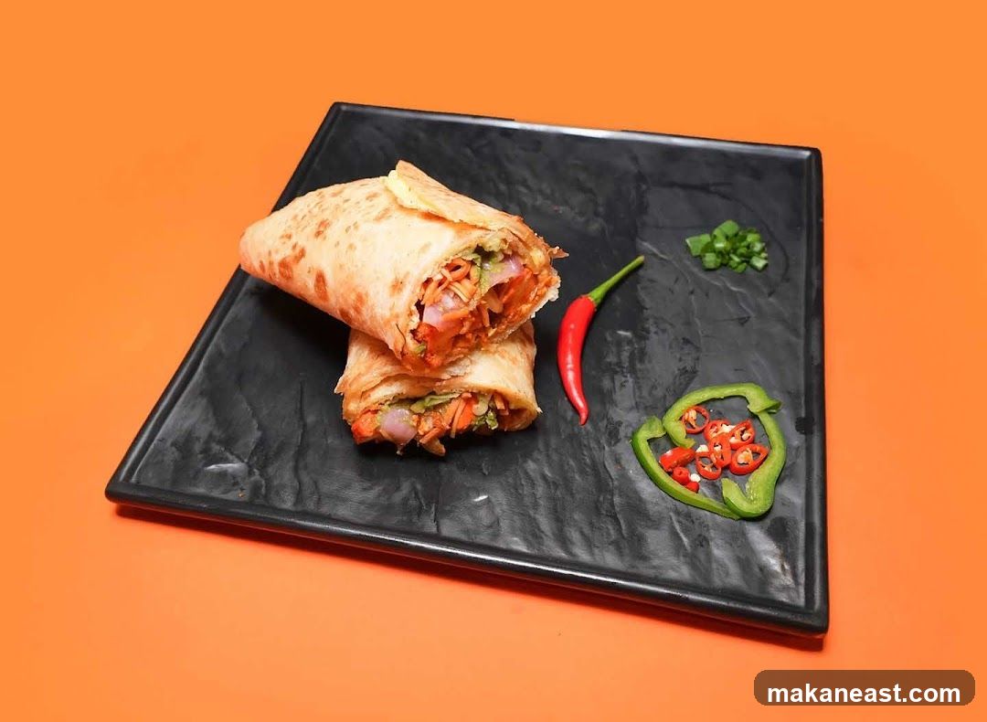 Two wraps on a black plate with garnishes