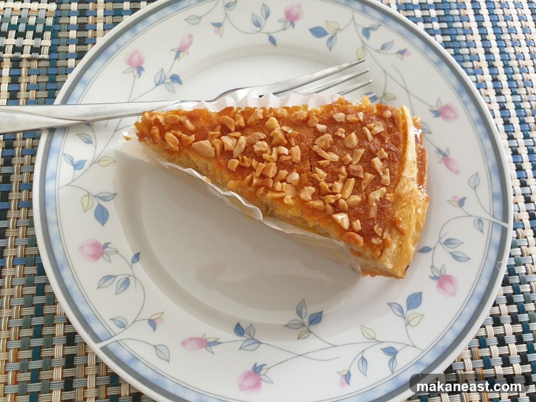 Slice of nut-topped pastry on a floral plate