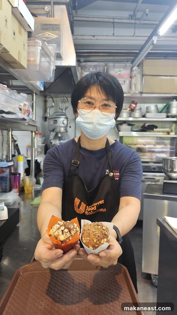 Baker holding two muffins