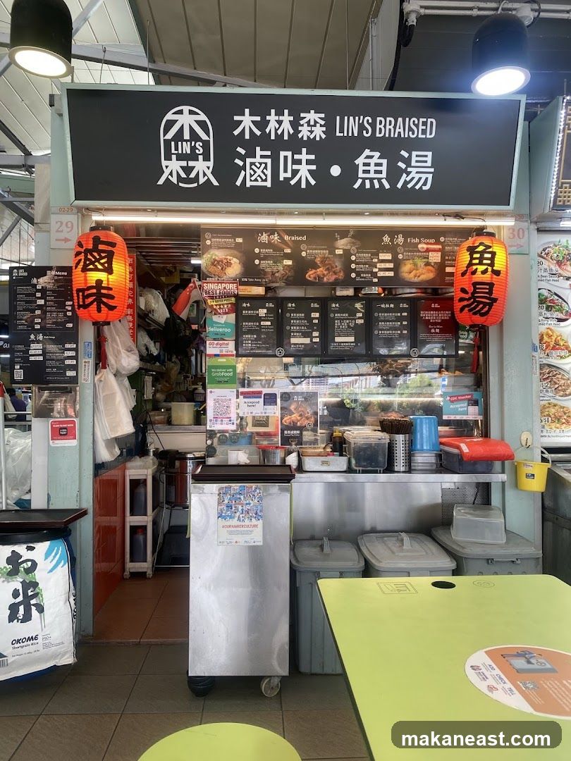 A food stall with a large black sign displaying "木林森 LIN'S BRAISED 滷味・魚湯" and two red lanterns. Below the sign are multiple menu boards with pictures of food items and prices. The stall appears to be in a hawker center, with tables and chairs visible in the foreground.