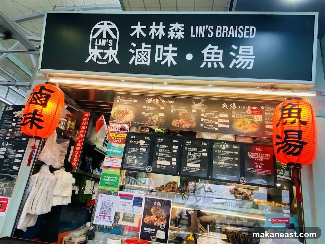 A food stall with a large black sign displaying the name "LIN'S BRAISED" in English and Chinese characters. Below the main sign, there are menu boards showcasing various dishes, including braised items and fish soup. Two large red lanterns with Chinese characters hang on either side of the stall. Various delivery service logos and a QR code are visible.