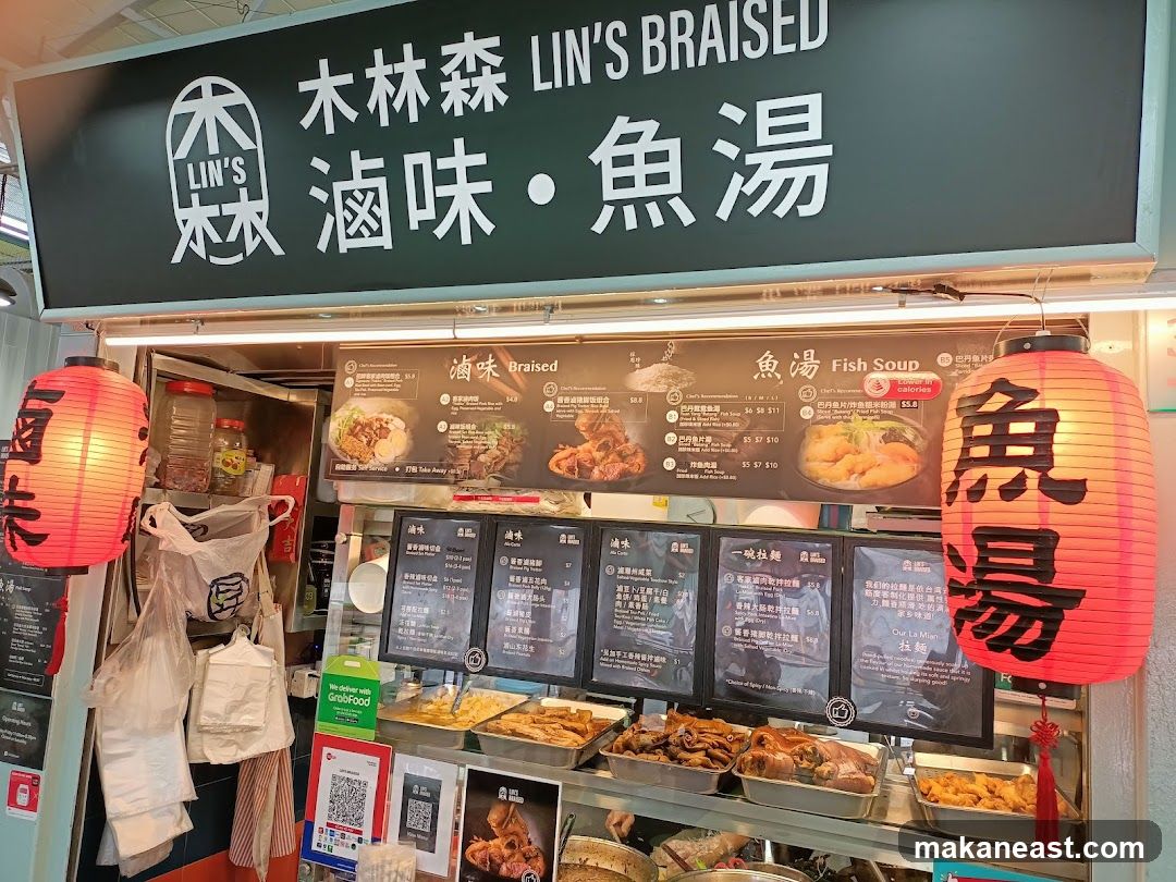 A food stall with a large sign displaying "LIN'S BRAISED 滷味・魚湯" in English and Chinese. Below the sign is a menu board with pictures of dishes and prices. Several food trays containing braised meats and other items are displayed in front of the stall. Two large red lanterns with Chinese characters hang on either side of the stall.
