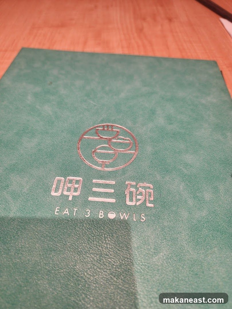 A green menu cover with a circular logo and Chinese characters above the text "EAT 3 BOWLS".