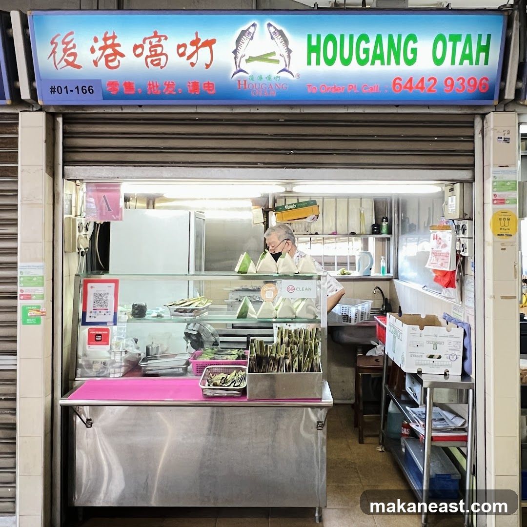 A shop front with a blue and white sign that reads "後港嚐咖 HOUGANG OTAH" and a phone number. Inside, a man is preparing food behind a display counter.