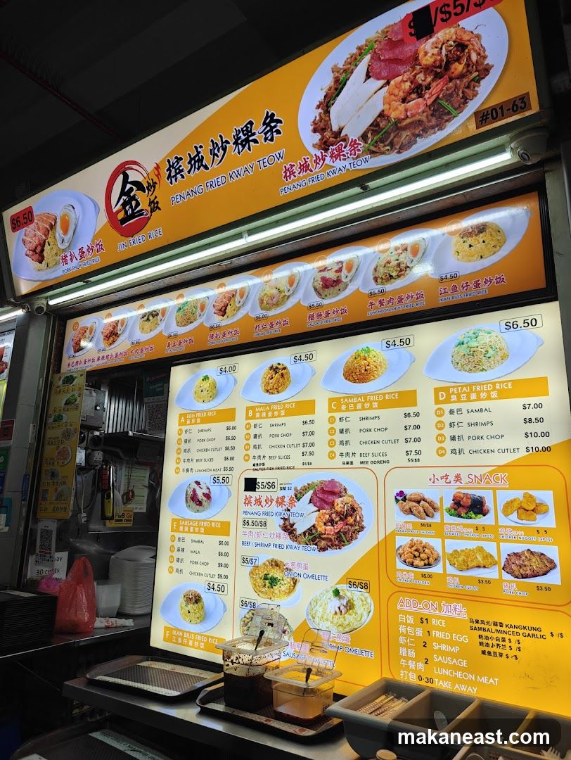 A brightly lit menu board displaying various fried rice dishes, fried kway teow, omelettes, snacks, and add-ons.