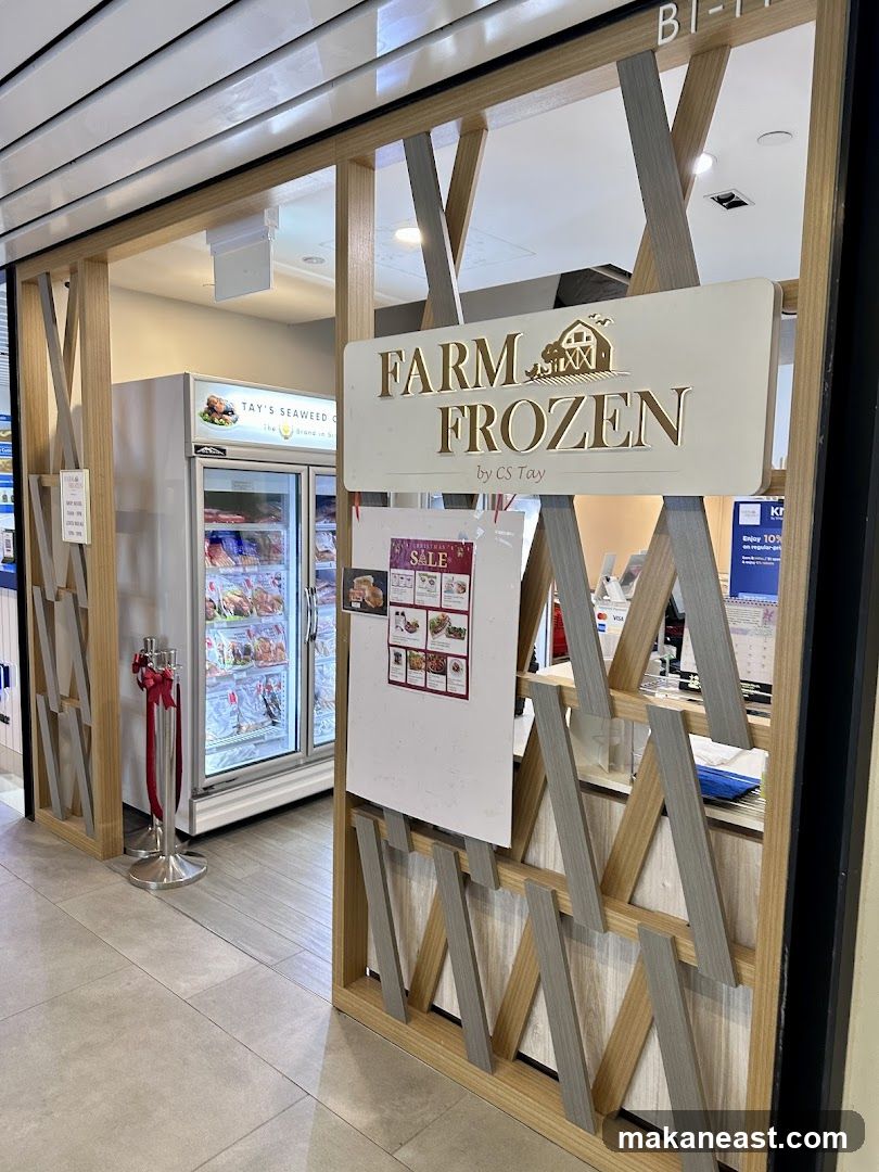 The exterior of a shop called Farm Frozen by CS Tay. A refrigerated display case filled with food items is visible to the left. A sign with the shop's name and logo is prominently displayed. A promotional flyer is attached to a board in front of the shop.