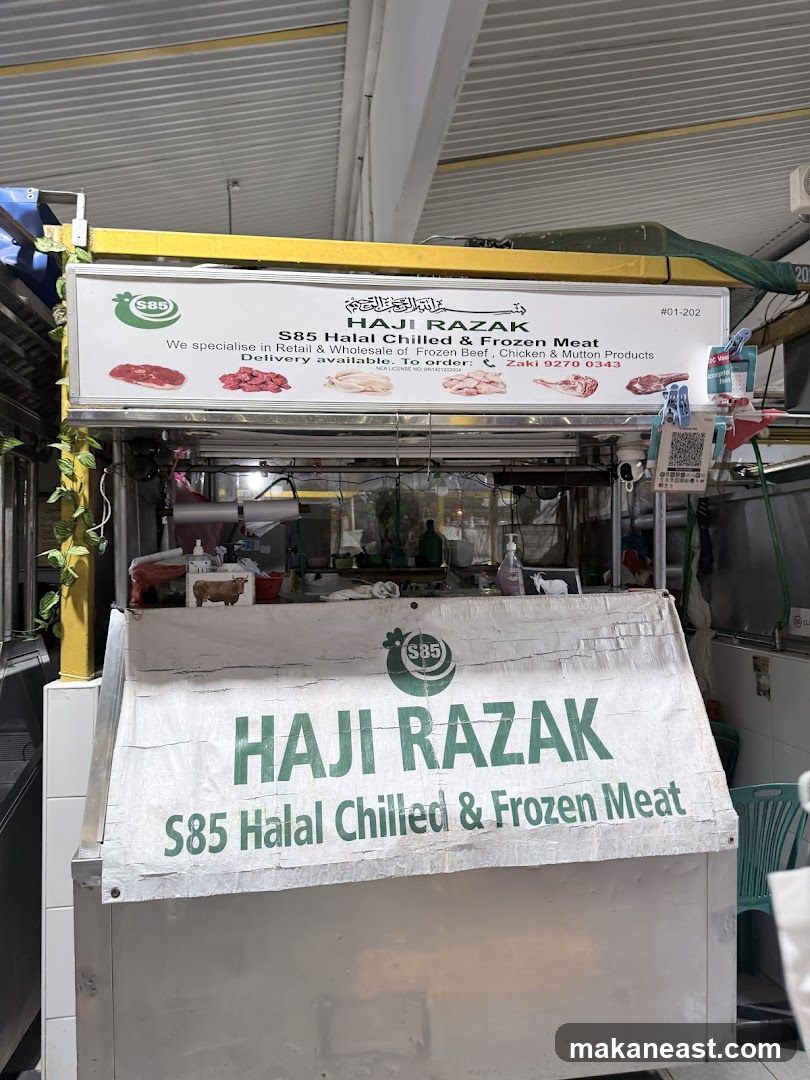 A storefront for a meat vendor named Haji Razak, specializing in Halal chilled and frozen beef, chicken, and mutton products. The shop offers both retail and wholesale services, with delivery available. Contact information for Zaki is provided for orders.