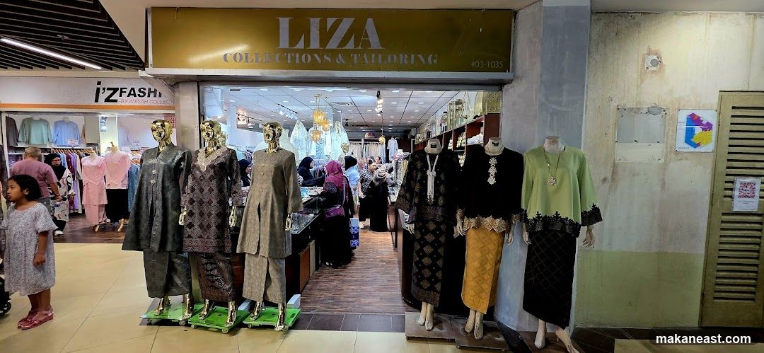 The storefront of Liza Collections & Tailoring features a large yellow sign with the store name and contact number. Inside, mannequins display traditional clothing, and customers browse racks of garments. To the left, another shop, i'Z Fashion, is visible with its own signage and displays of clothing.