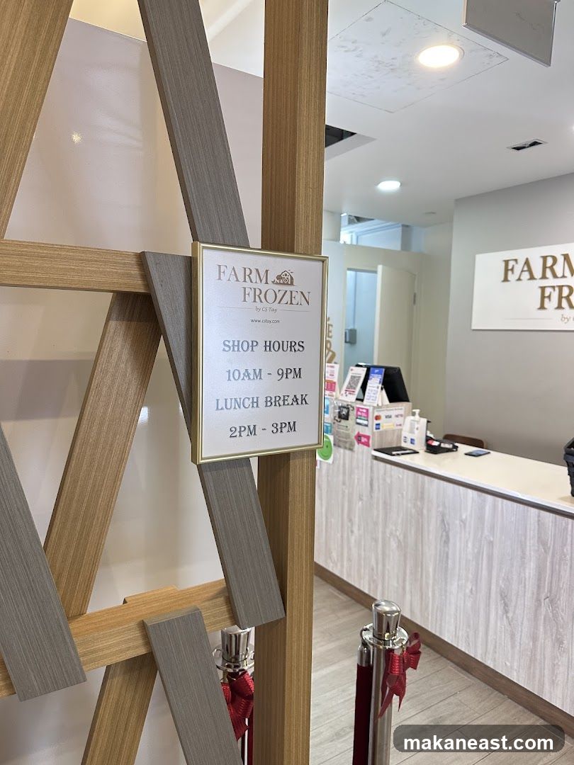 A sign displays the shop hours for Farm Frozen by CS Tay. The hours are 10 AM to 9 PM, with a lunch break from 2 PM to 3 PM. The background shows a counter with payment terminals and a sign with the business name.