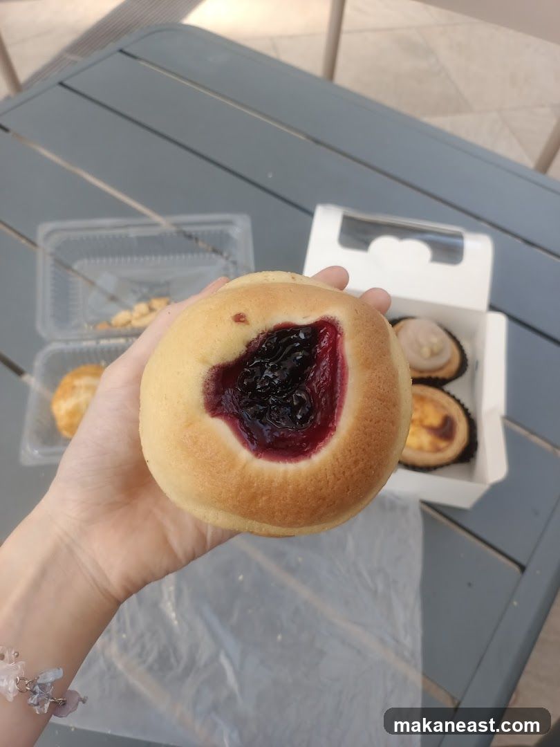 Hand holding a pastry with jam filling