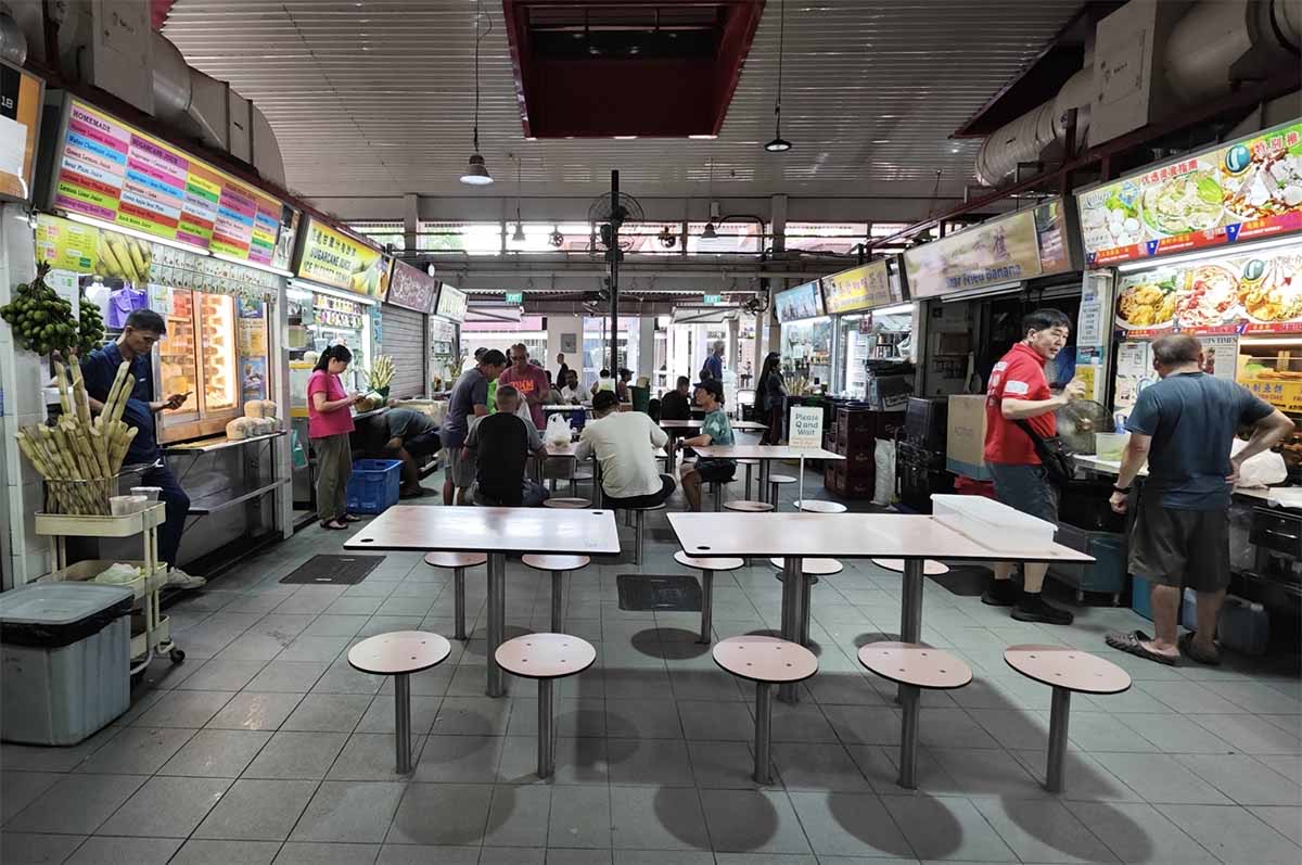 Interior of Changi Village Hawker Centre with open stalls and round tables