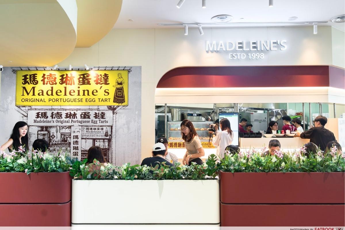 Interior of the new Madeleine's Original Portuguese Egg Tarts cafe at Aperia Mall, styled as a Macanese cha chaan teng with seating and a counter display